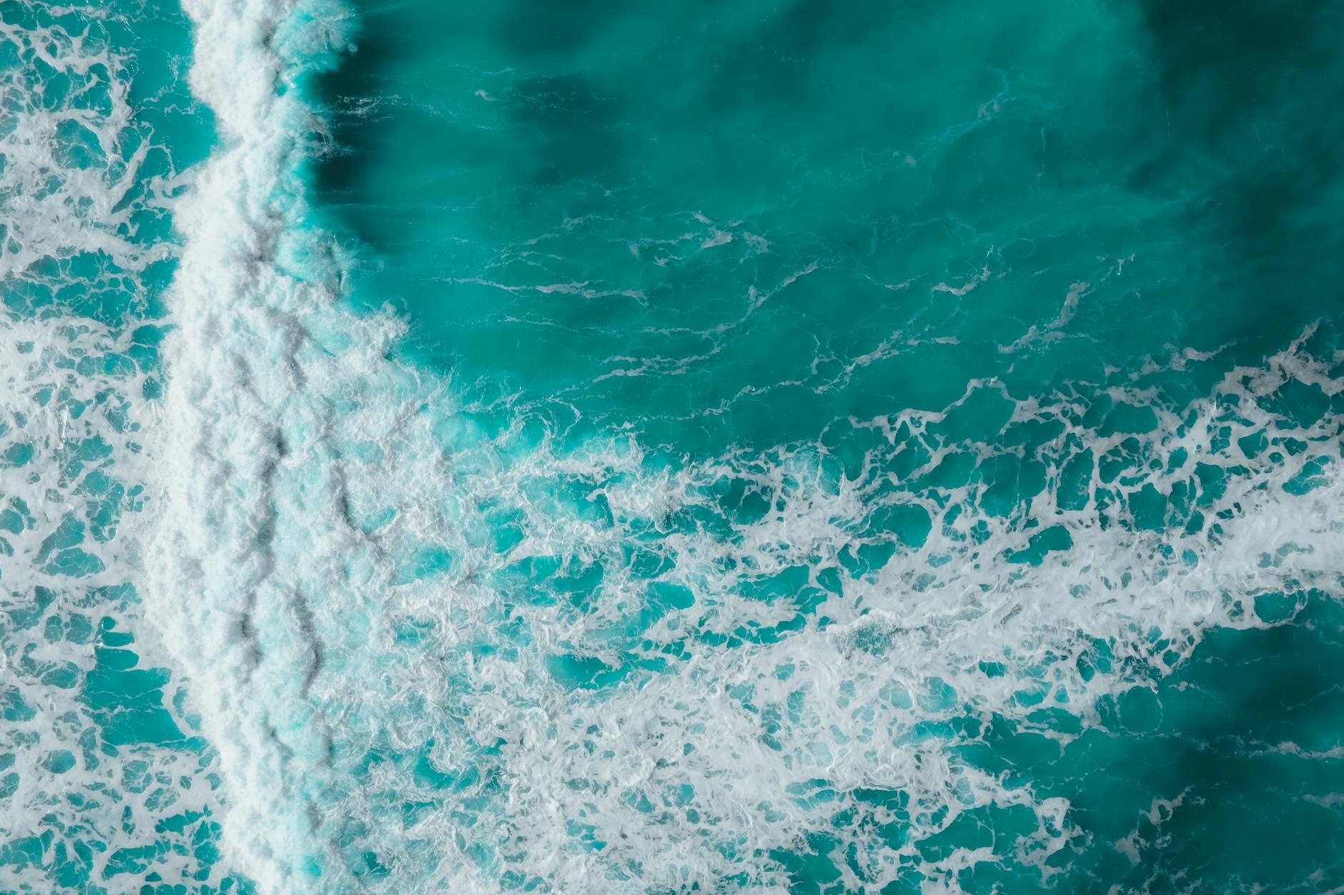 A breathtaking aerial view of turquoise ocean waves crashing on the shore.