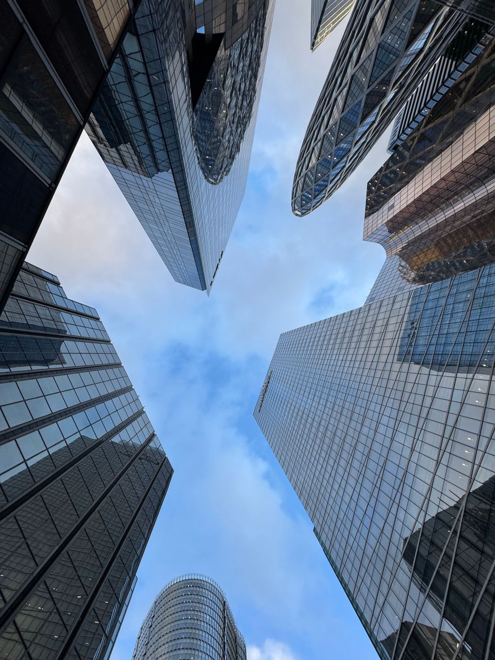 Upward view of modern skyscrapers in La Défense, Paris, reflecting a vibrant urban atmosphere.