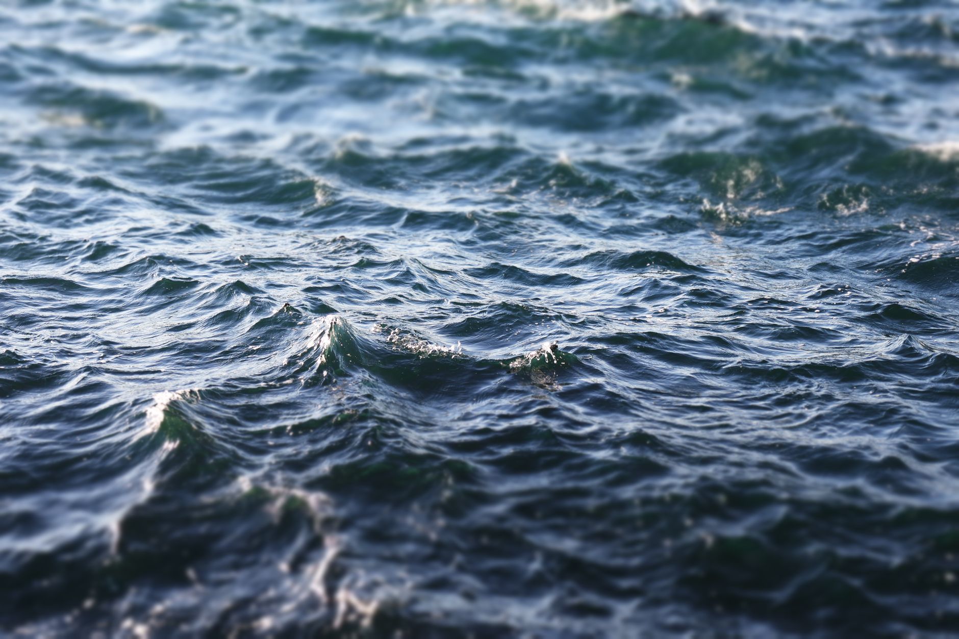 Close-up image of dynamic ocean waves under a bright blue sky.