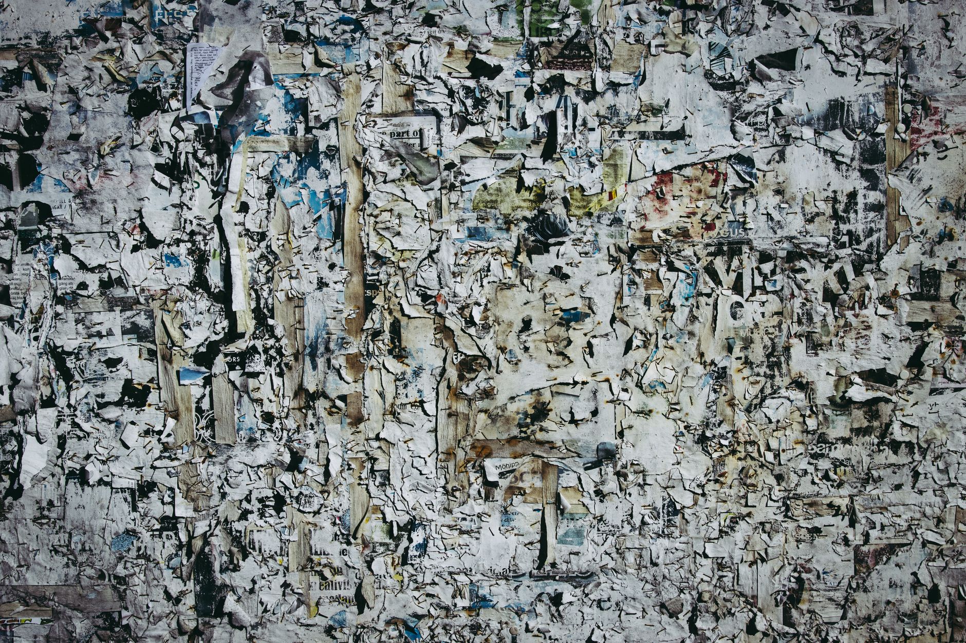 A textured wall with layers of torn and weathered paper for artistic backgrounds.
