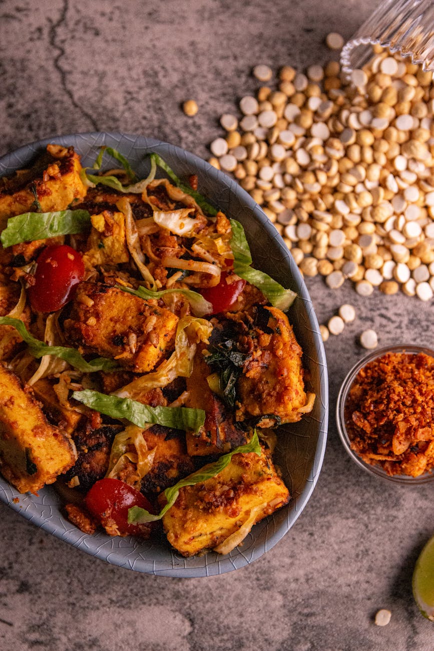 A delicious tofu stir-fry with cherry tomatoes, lettuce, and spices served in a rustic style.