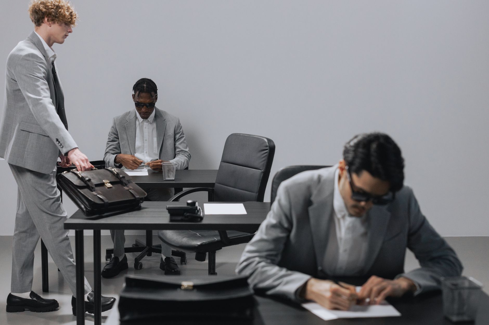 Business office with diverse employees in gray suits working at desks in an indoor setting.