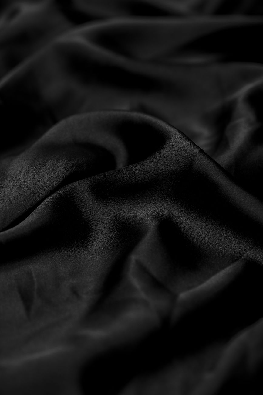 A close-up of luxurious black silk fabric with soft folds, offering a smooth and elegant texture.