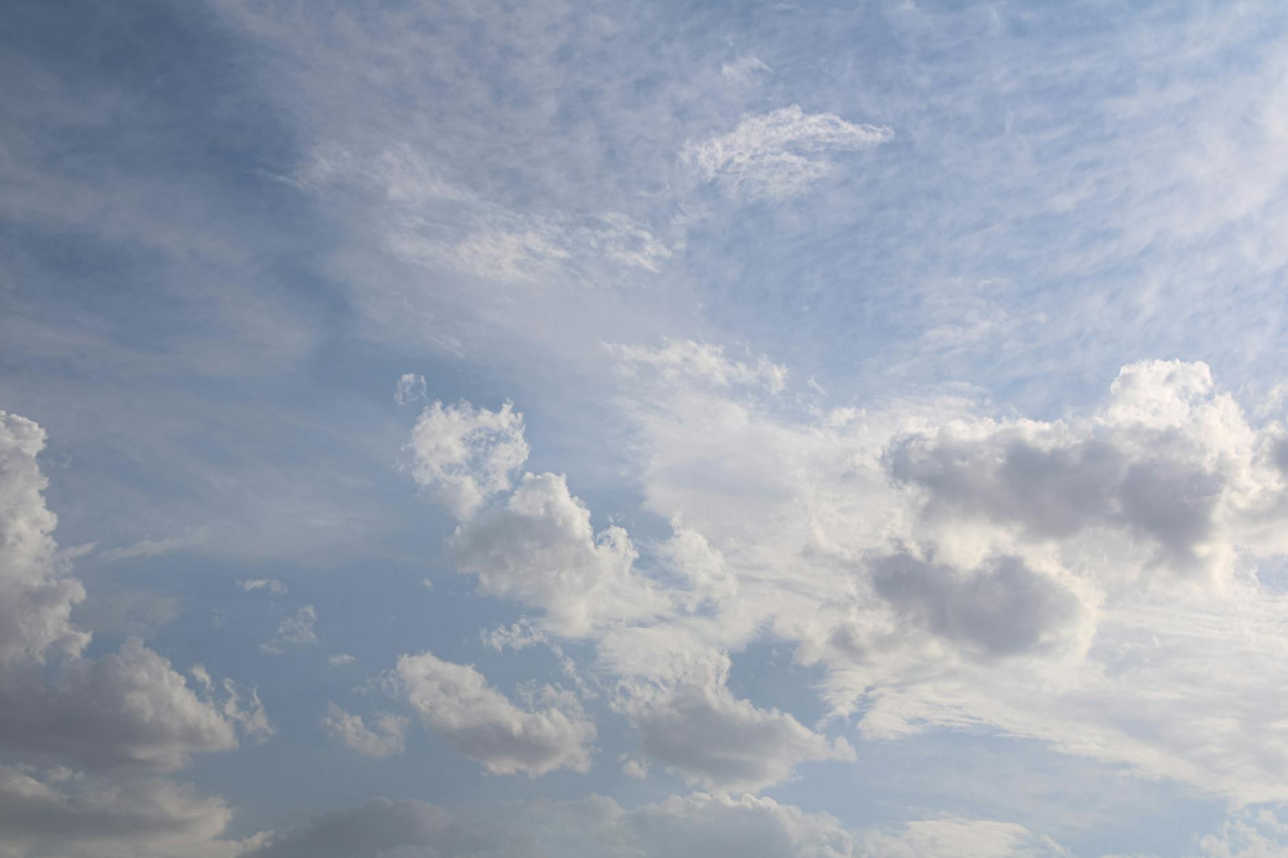 Serene view of a blue sky filled with scattered fluffy clouds on a sunny day.