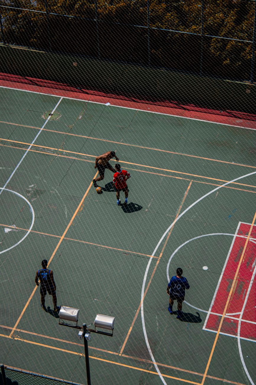 Aerial shot of four men playing basketball on an outdoor court.