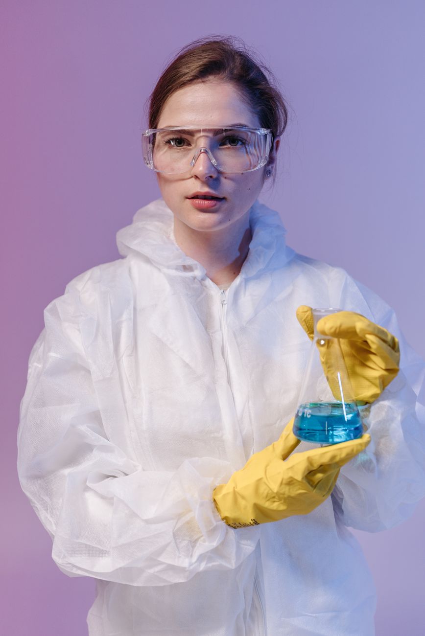 A woman in protective gear conducting laboratory research with a beaker.