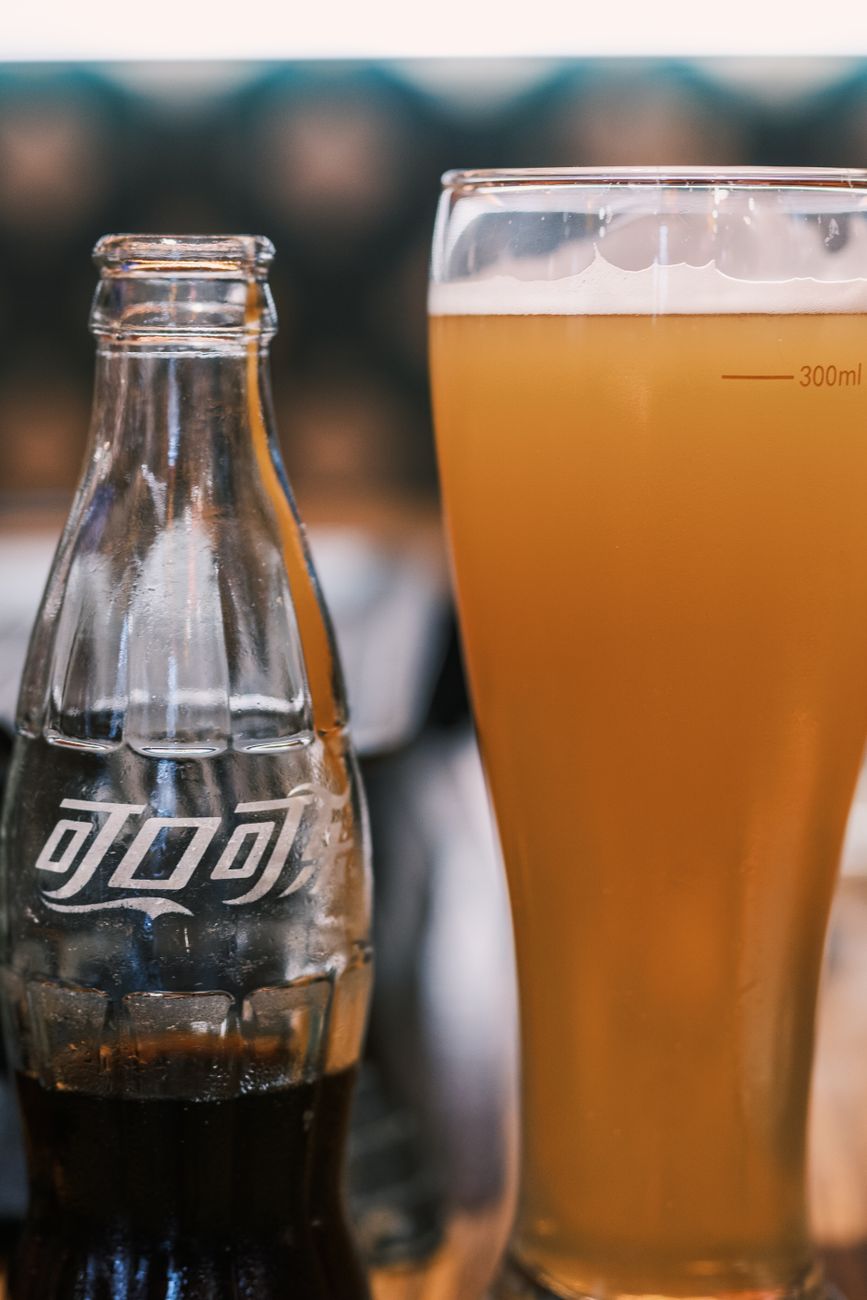 Glass of beer and soft drink bottle on a table in Beijing, China.