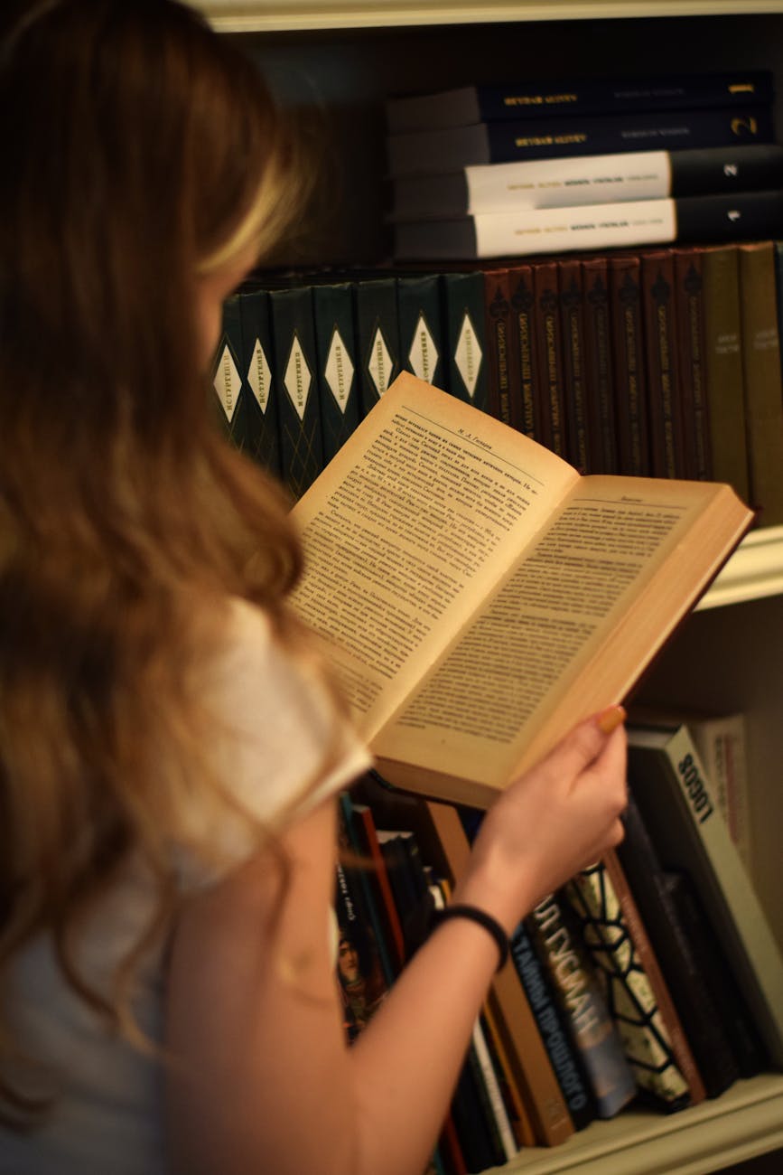 A young woman reading in front of a bookshelf filled with books, creating a warm, vintage feel.