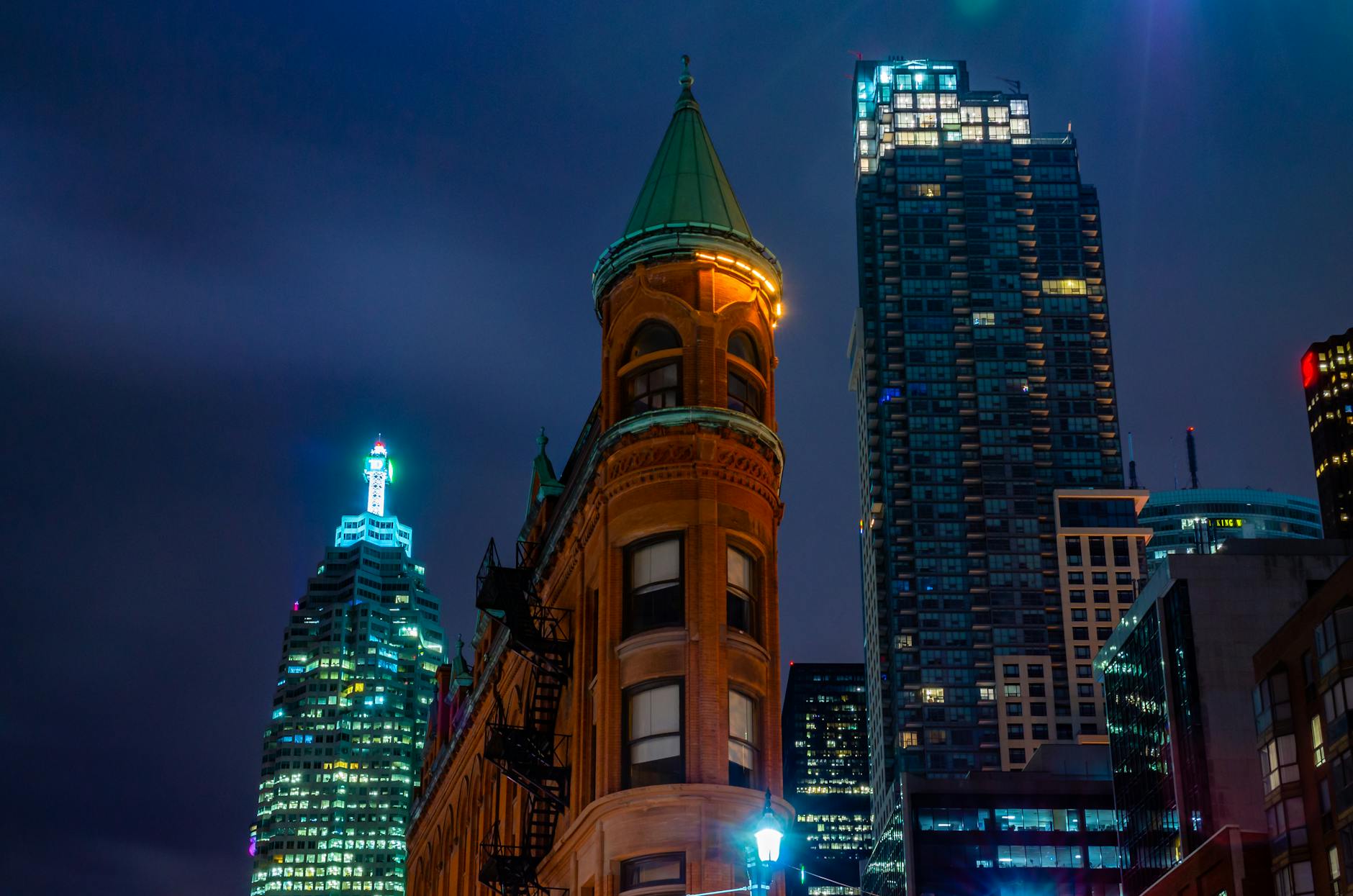 Stunning view of Toronto's iconic Gooderham Building illuminated around city skyscrapers at night.
