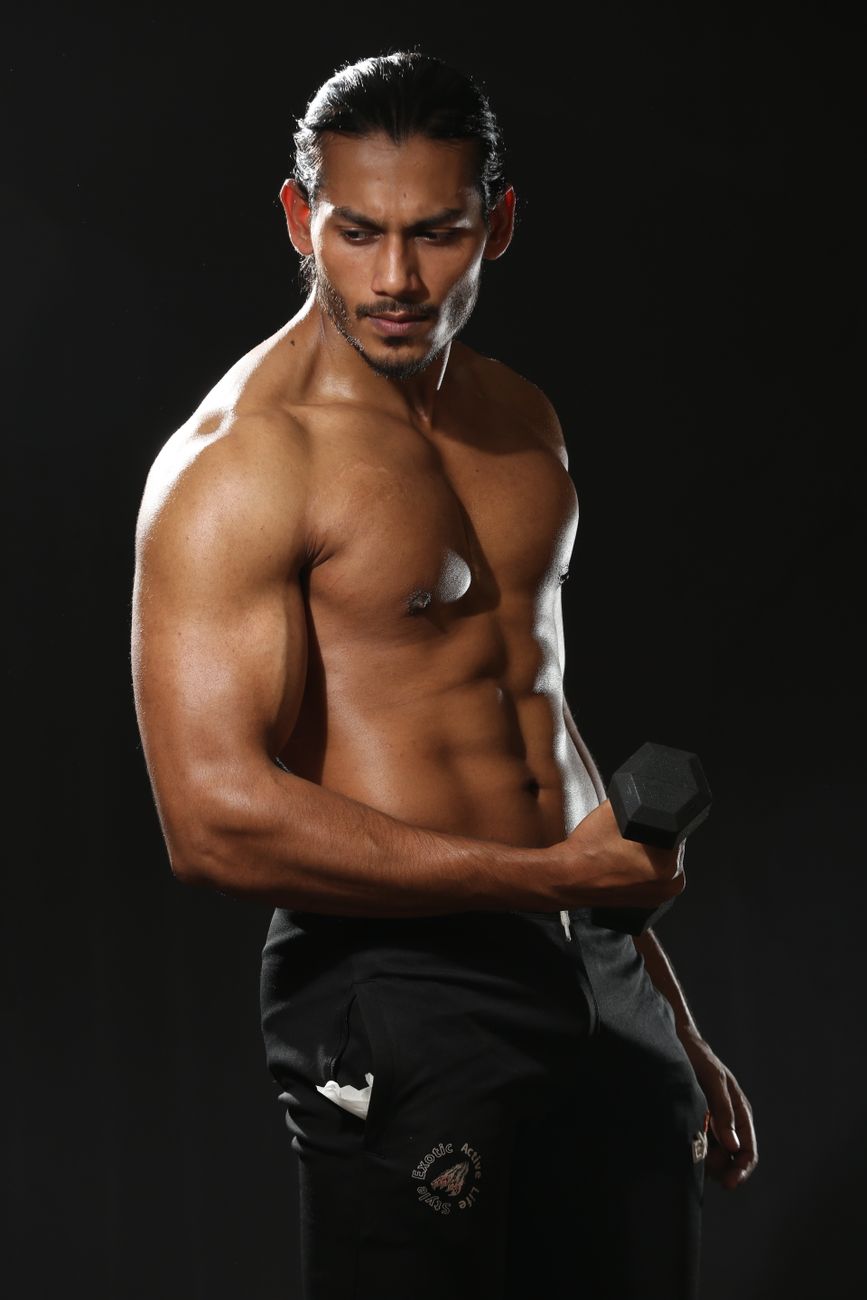 Athletic man demonstrating strength by lifting a dumbbell during a studio photoshoot.