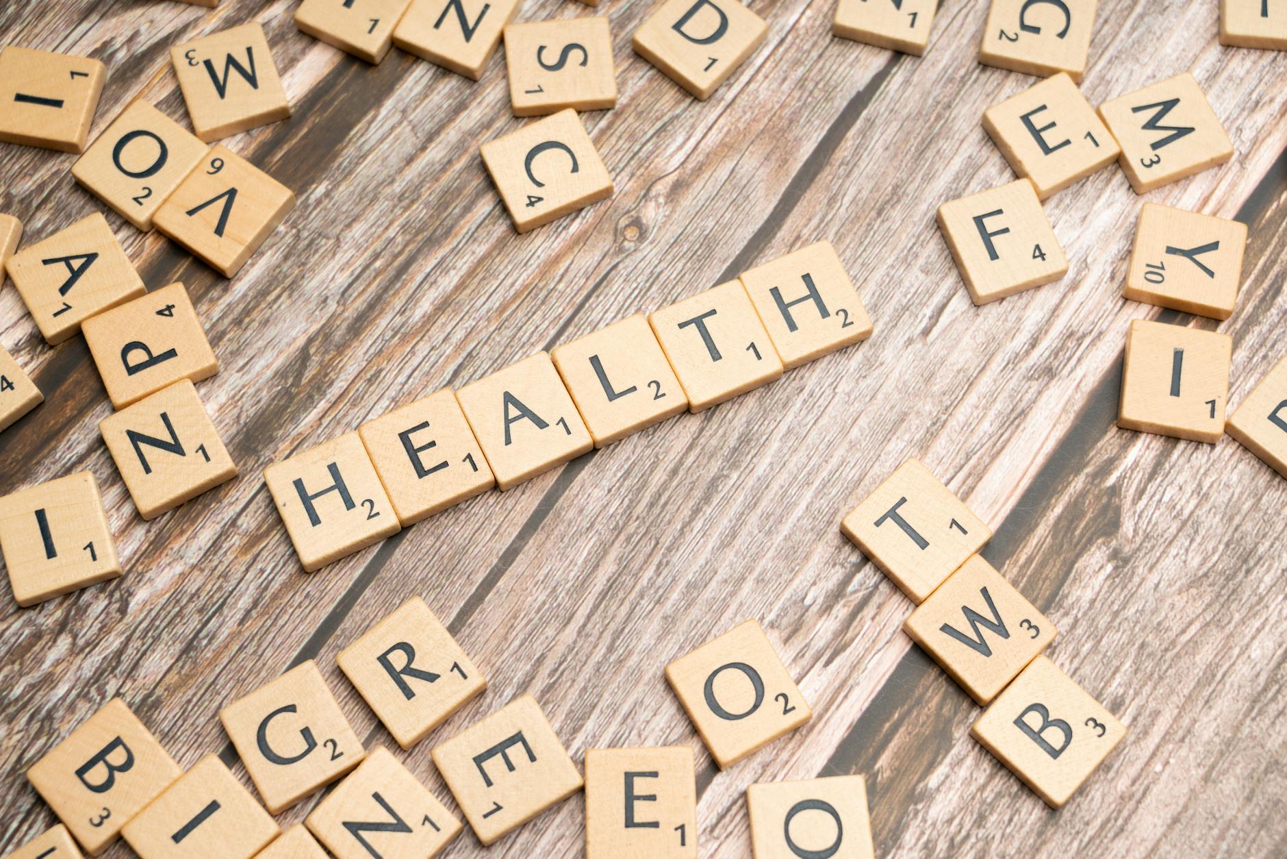 Scrabble tiles spelling 'HEALTH' on wooden surface, symbolizing wellness.