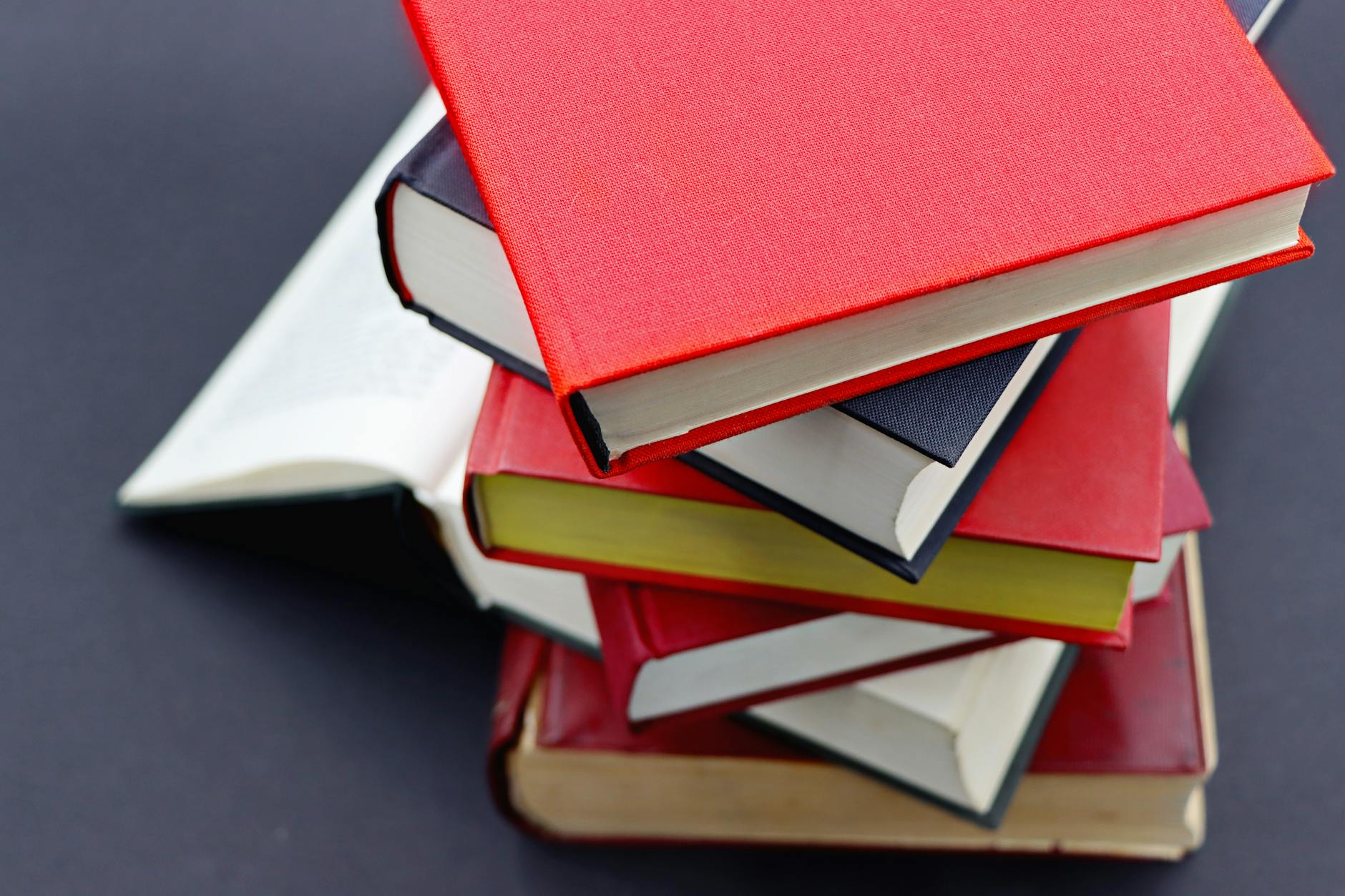 Pile of assorted hardcover books with colorful covers, perfect for study or literature themes.