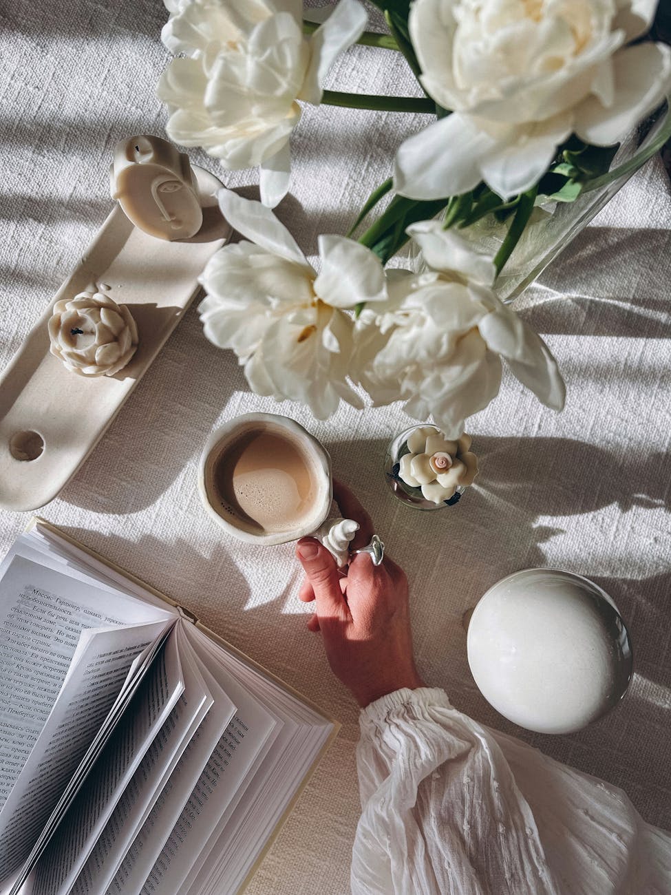Serene flat lay with coffee, white flowers, and an open book, perfect for a cozy lifestyle scene.