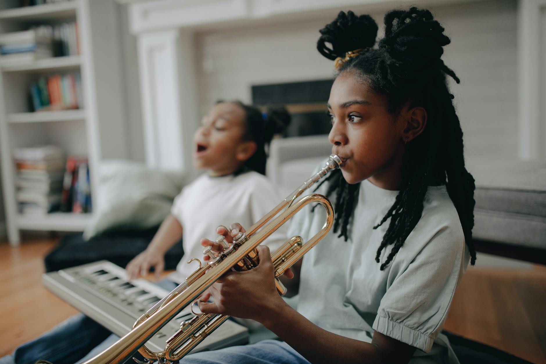 Girl playing trumpet with sibling at home, enjoying music time.