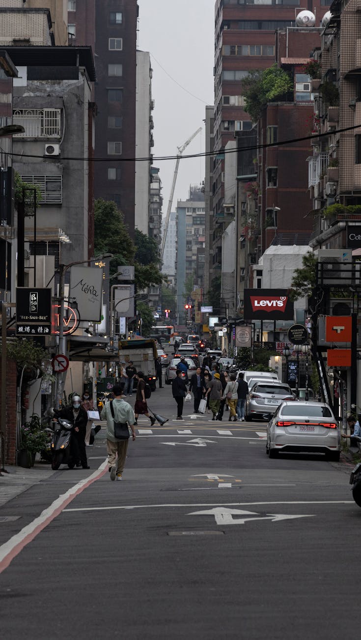 Crowded city street lined with high-rise buildings, capturing urban life and traffic.