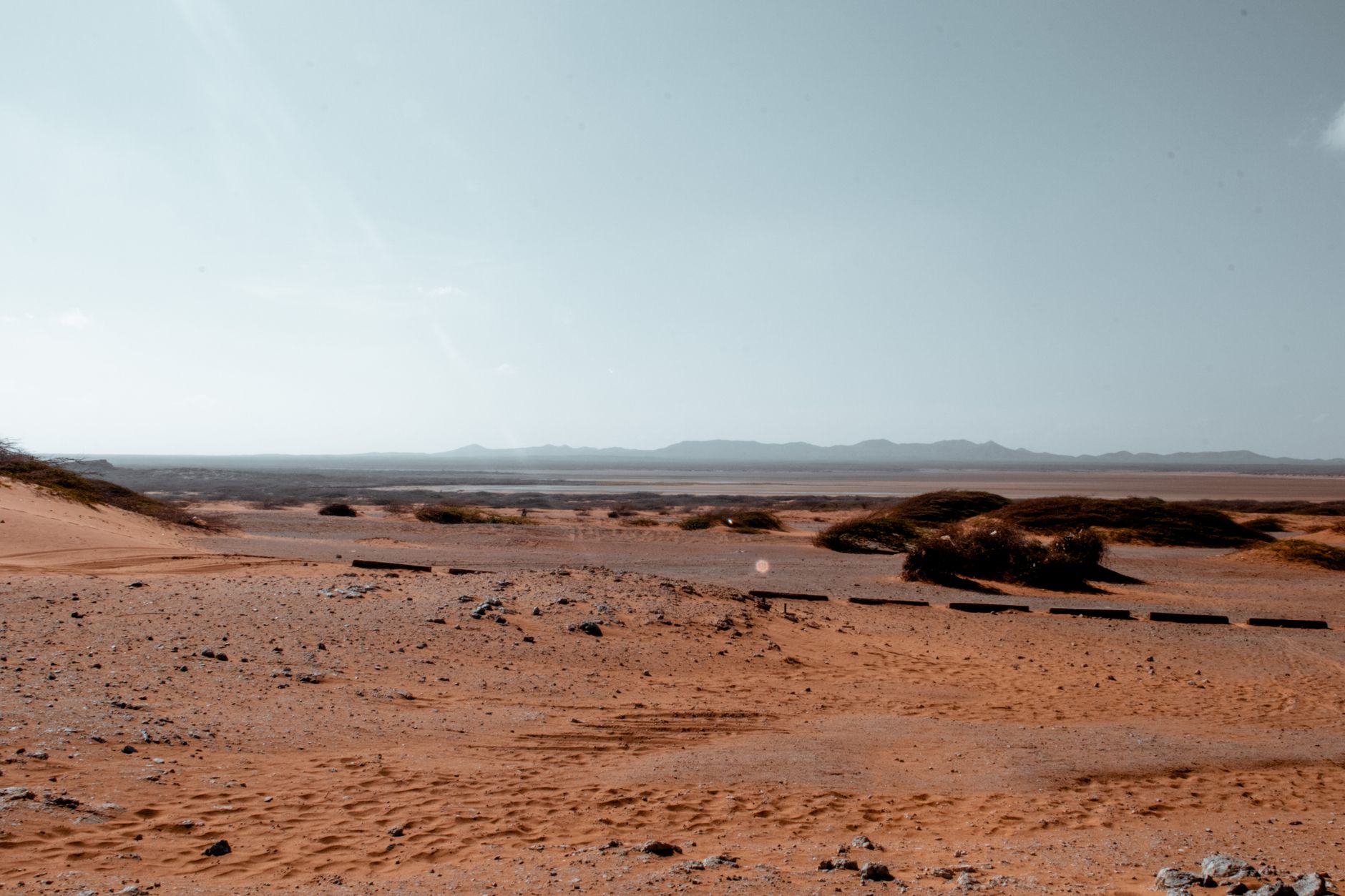 Vast desert landscape with sand dunes and clear blue sky, captured from a high vantage point.