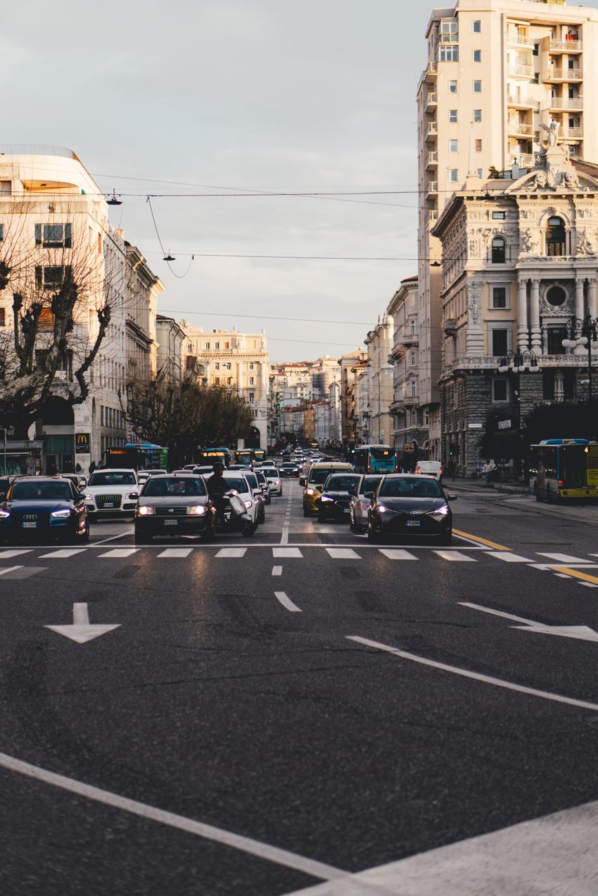 Traffic flows through a bustling city street in Trieste, Italy, showcasing urban life.