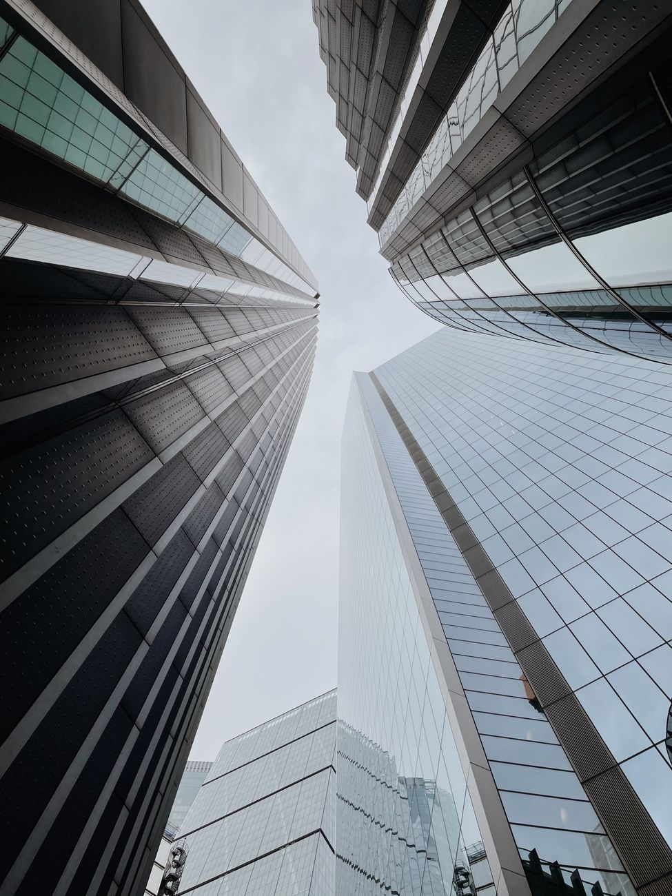 Dramatic low angle view of towering modern skyscrapers reaching into the cloudy sky.