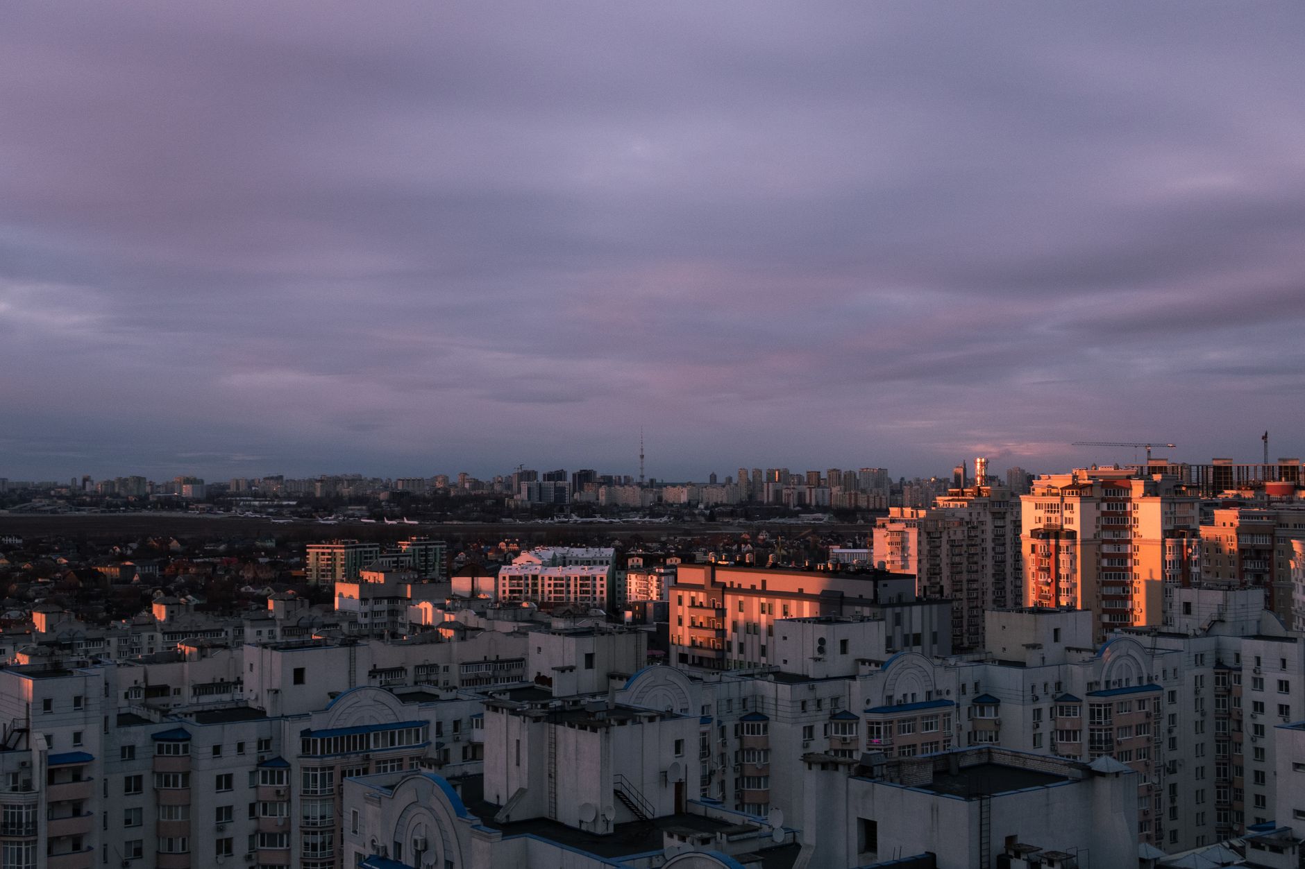 Aerial view of Kyiv city with striking clouds and sunset light over the urban skyline.