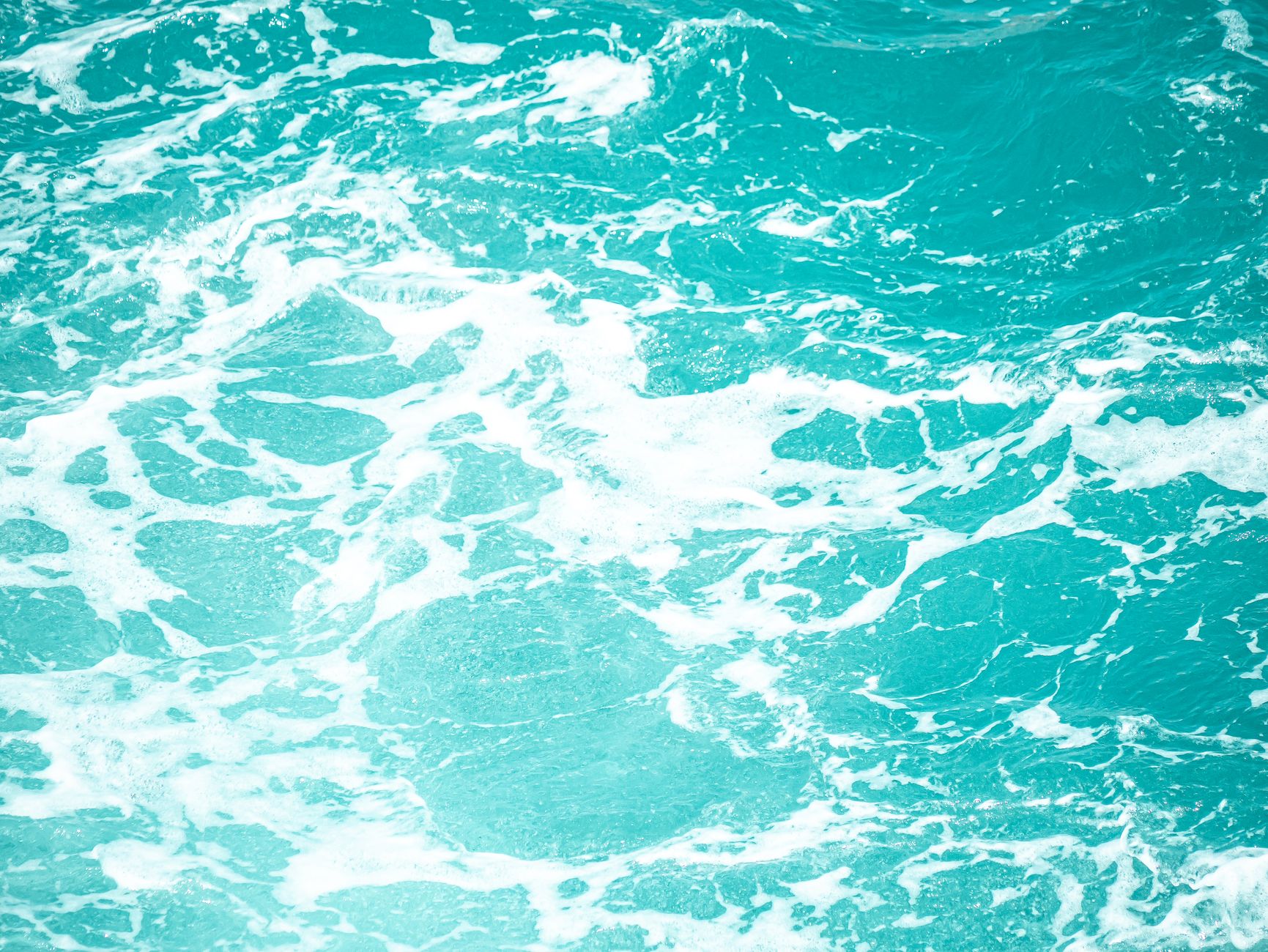 A close-up view of turquoise ocean waves and white foam, capturing the dynamic and refreshing movement of the sea.