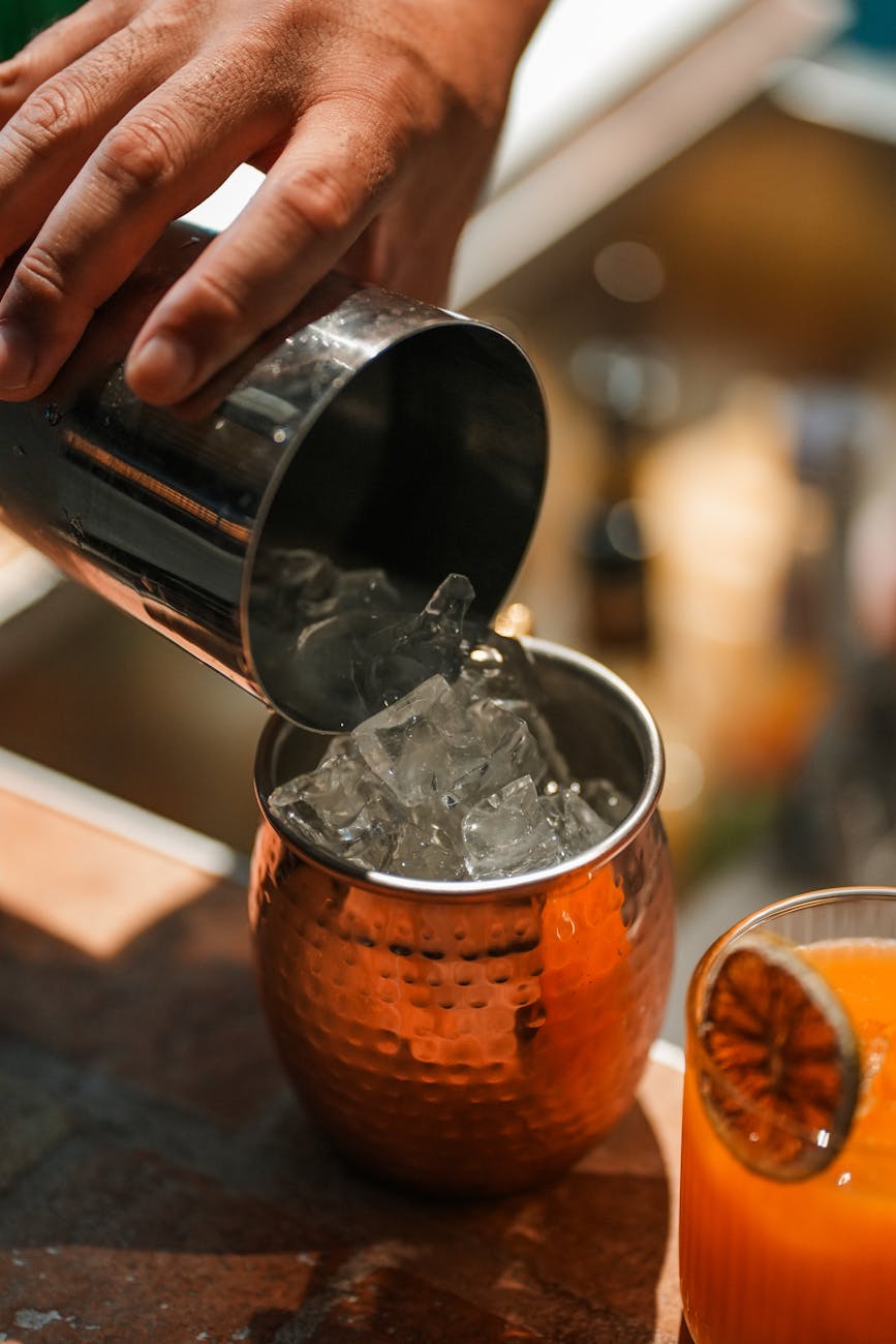 Close-up of a refreshing cocktail being prepared in a copper mug with ice, perfect for summer days.