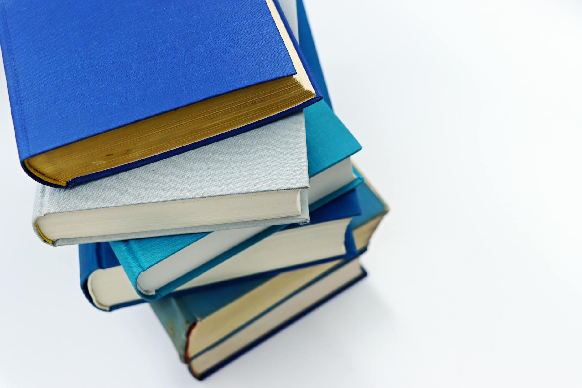 A vertical stack of books with blue covers on a white background symbolizes education and literature.