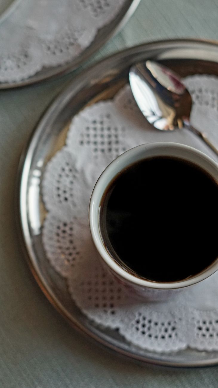 A cup of Turkish coffee served on a silver tray with a doily