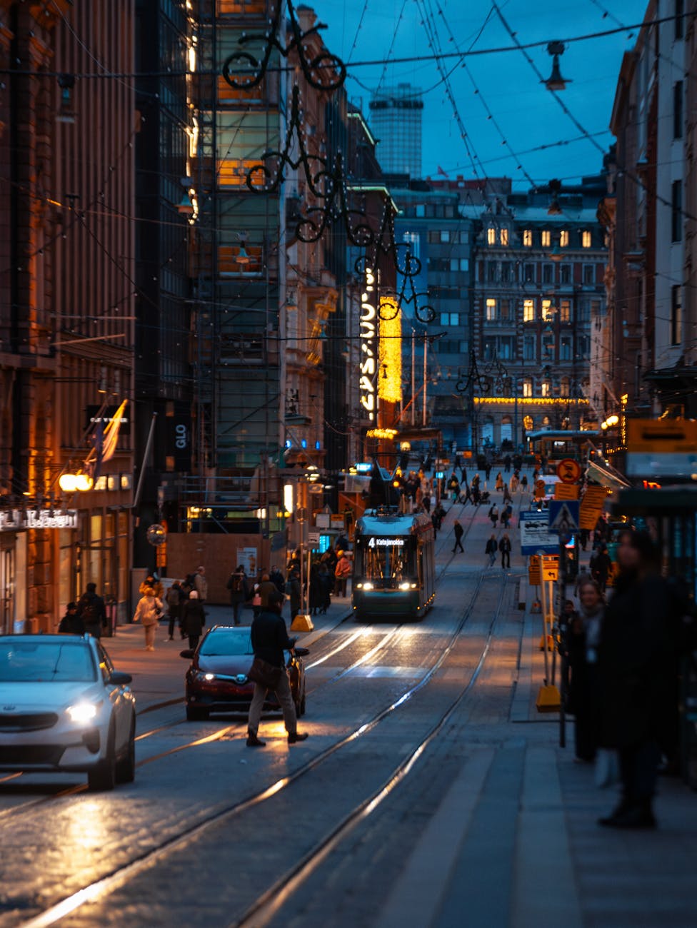 Urban evening scene in Helsinki, Finland with tram and pedestrians, showcasing city life.