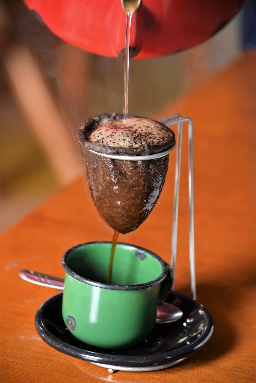 Close-up of traditional Brazilian coffee being brewed with cloth filter into a green cup.