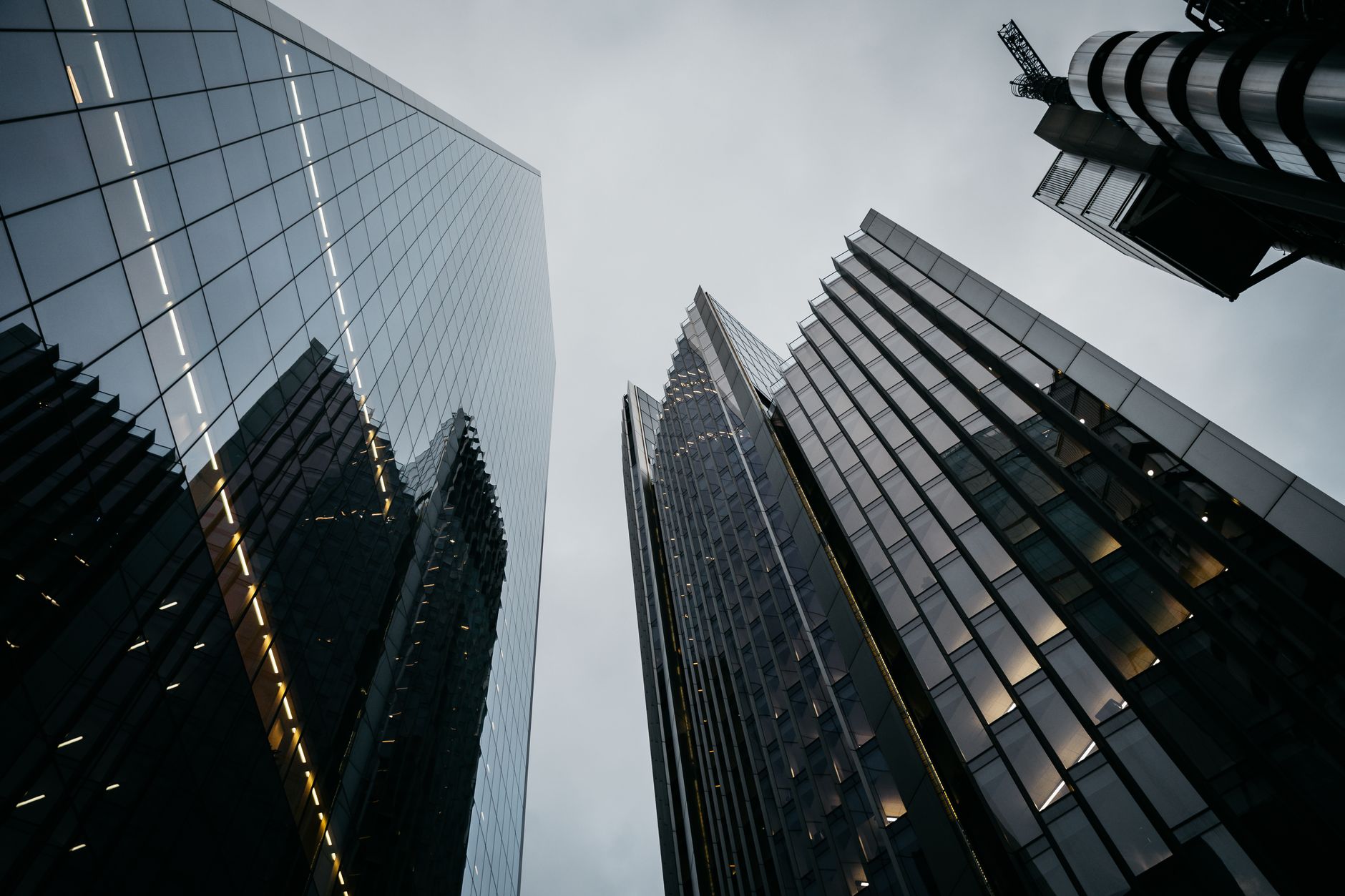 Low angle view of modern skyscrapers in London. Urban architecture stands tall under a cloudy sky.