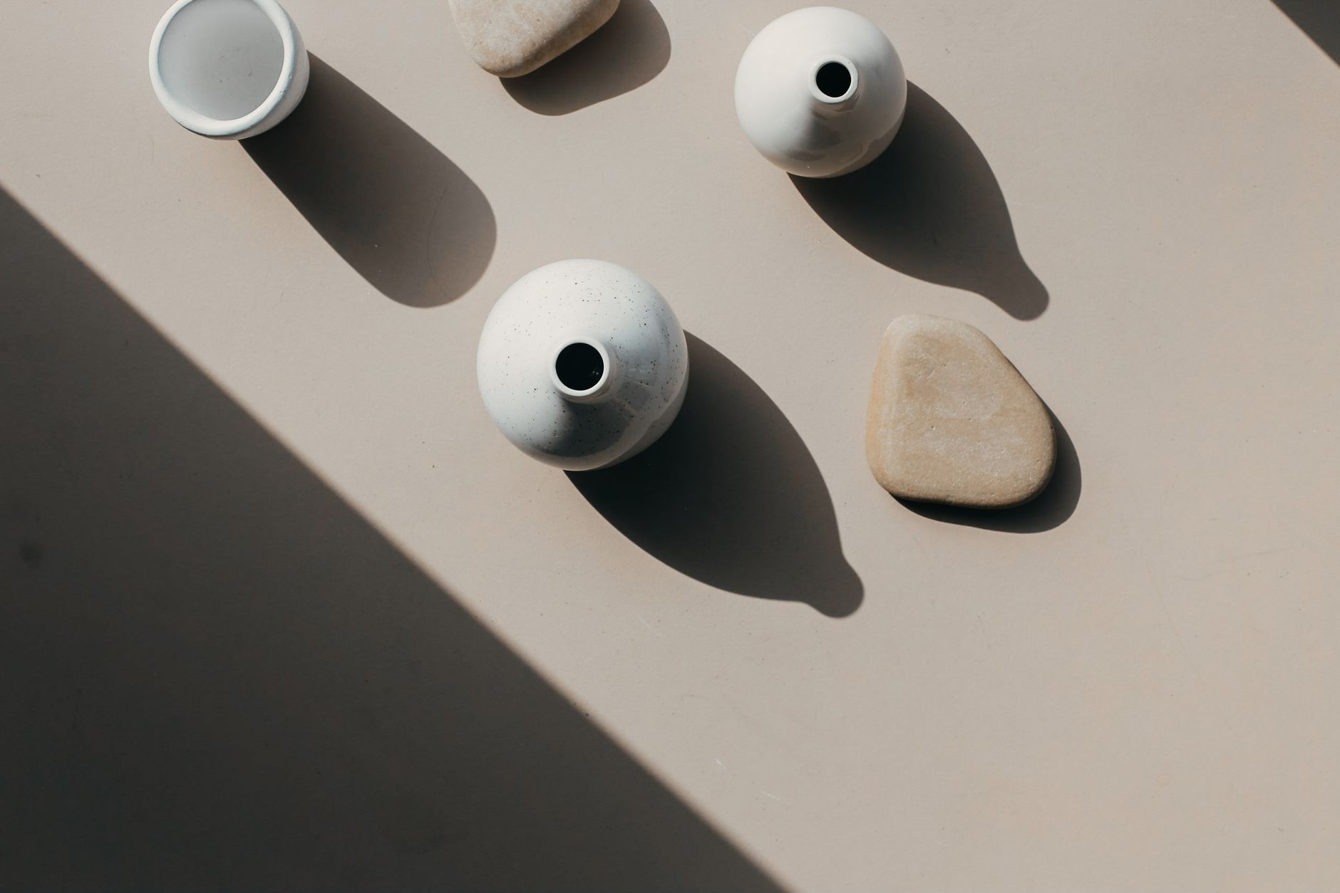Aesthetic overhead composition of ceramic vases and stones casting artistic shadows.