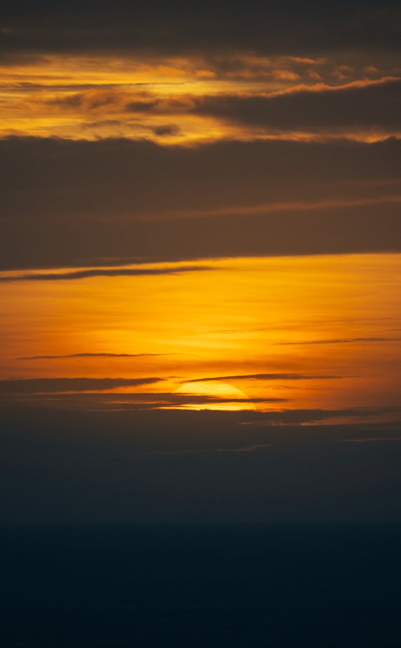 Beautiful golden sunset over a vast ocean horizon with layered clouds in a dramatic evening sky.