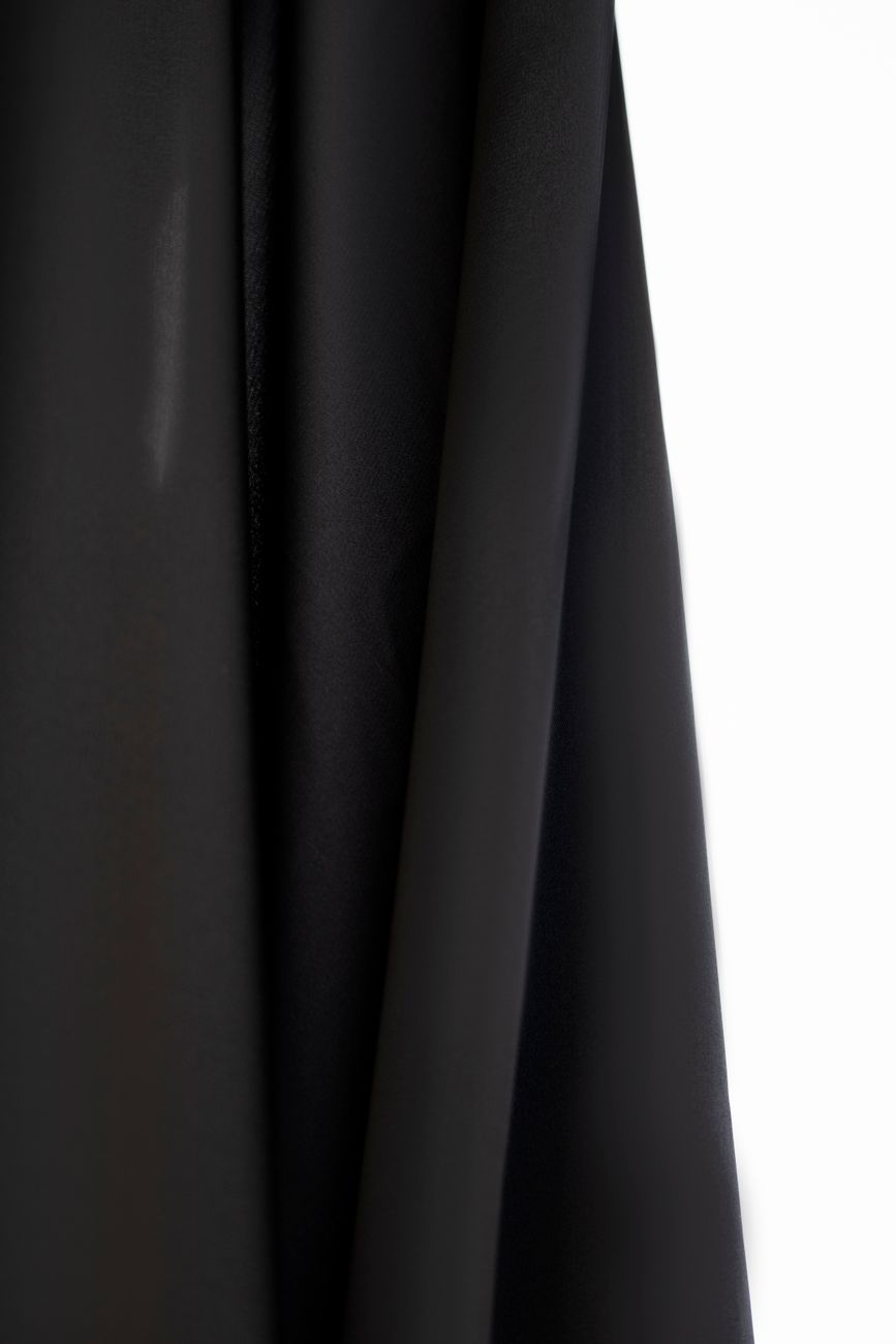 A minimalist still life of black drapes against a contrasting white backdrop.
