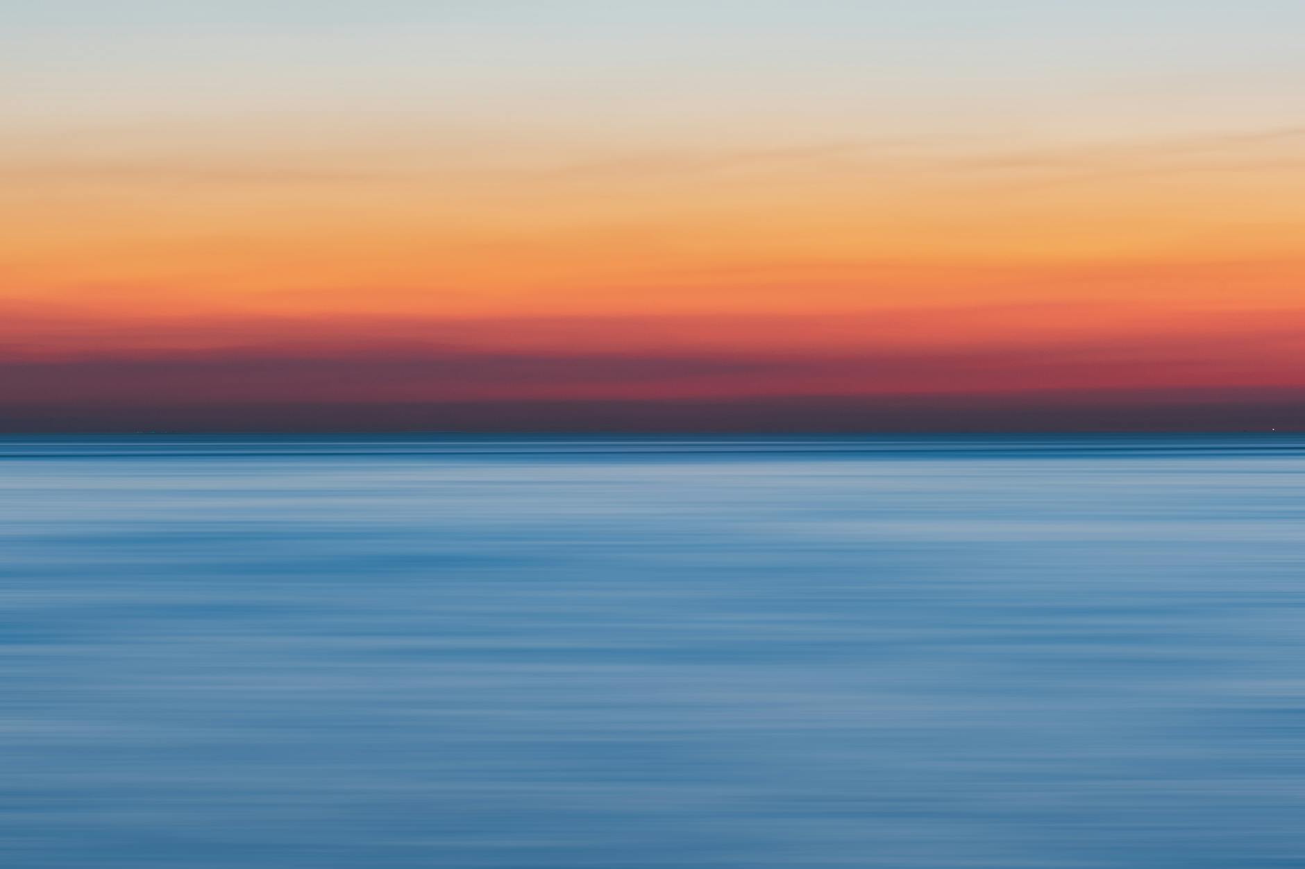 A colorful sunset over a calm ocean, perfect for vibrant backgrounds.