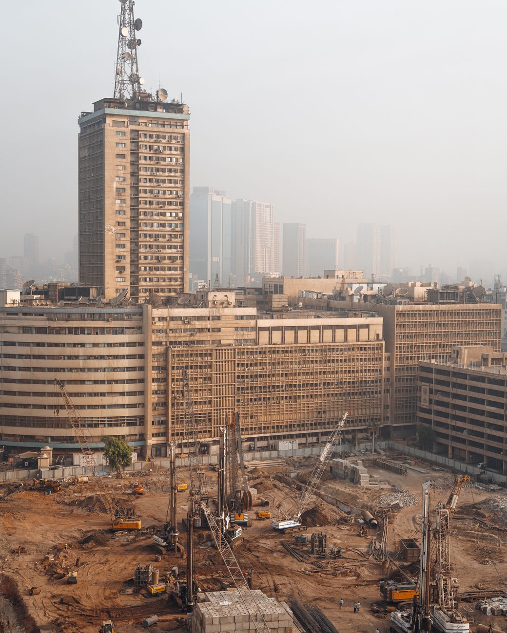 Aerial view of Cairo construction site with hazy skyline and high-rise buildings in Egypt.