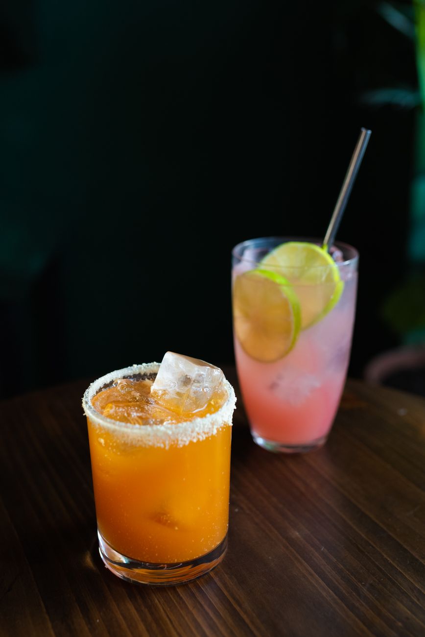 Close-up of two refreshing summer cocktails with citrus garnishes on a wooden table.
