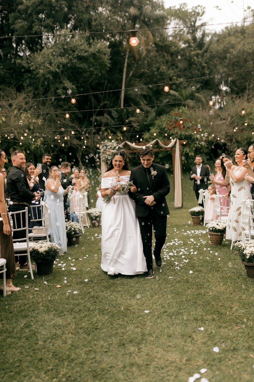 Bride and groom walking down the aisle in a decorated garden ceremony.