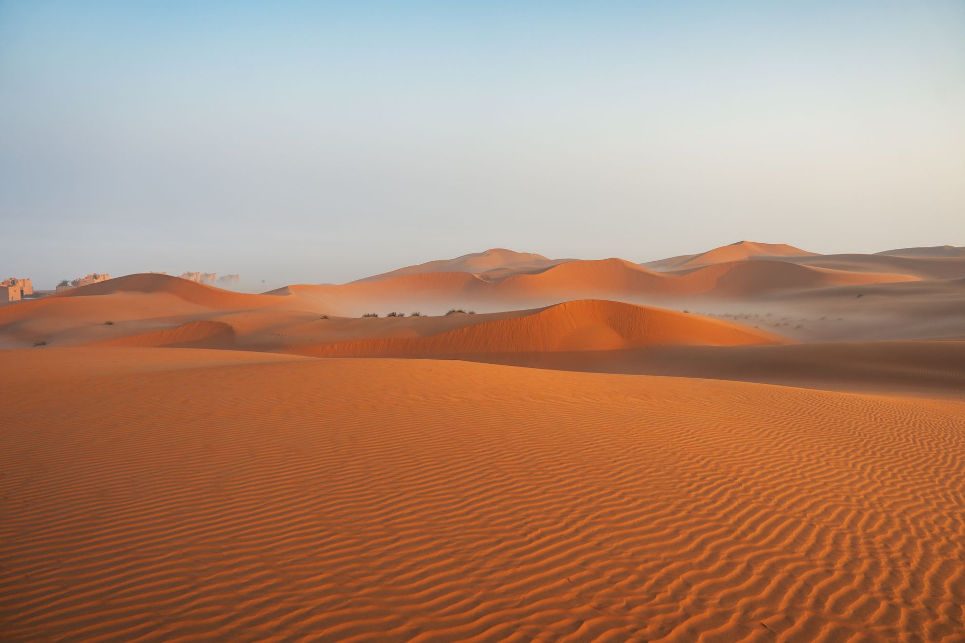 Expansive desert landscape with golden sand dunes illuminated by sunrise, showcasing natural patterns and tranquility.