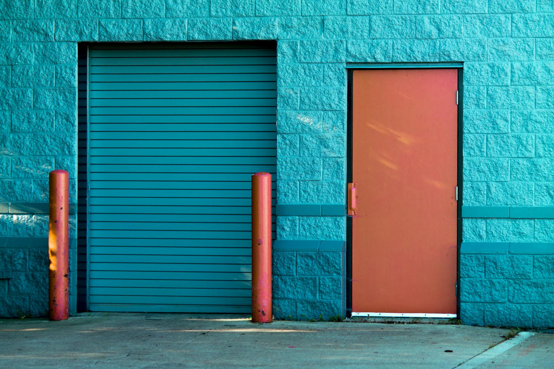 Vivid blue wall with a closed door and shutter in Valparaiso's urban setting.