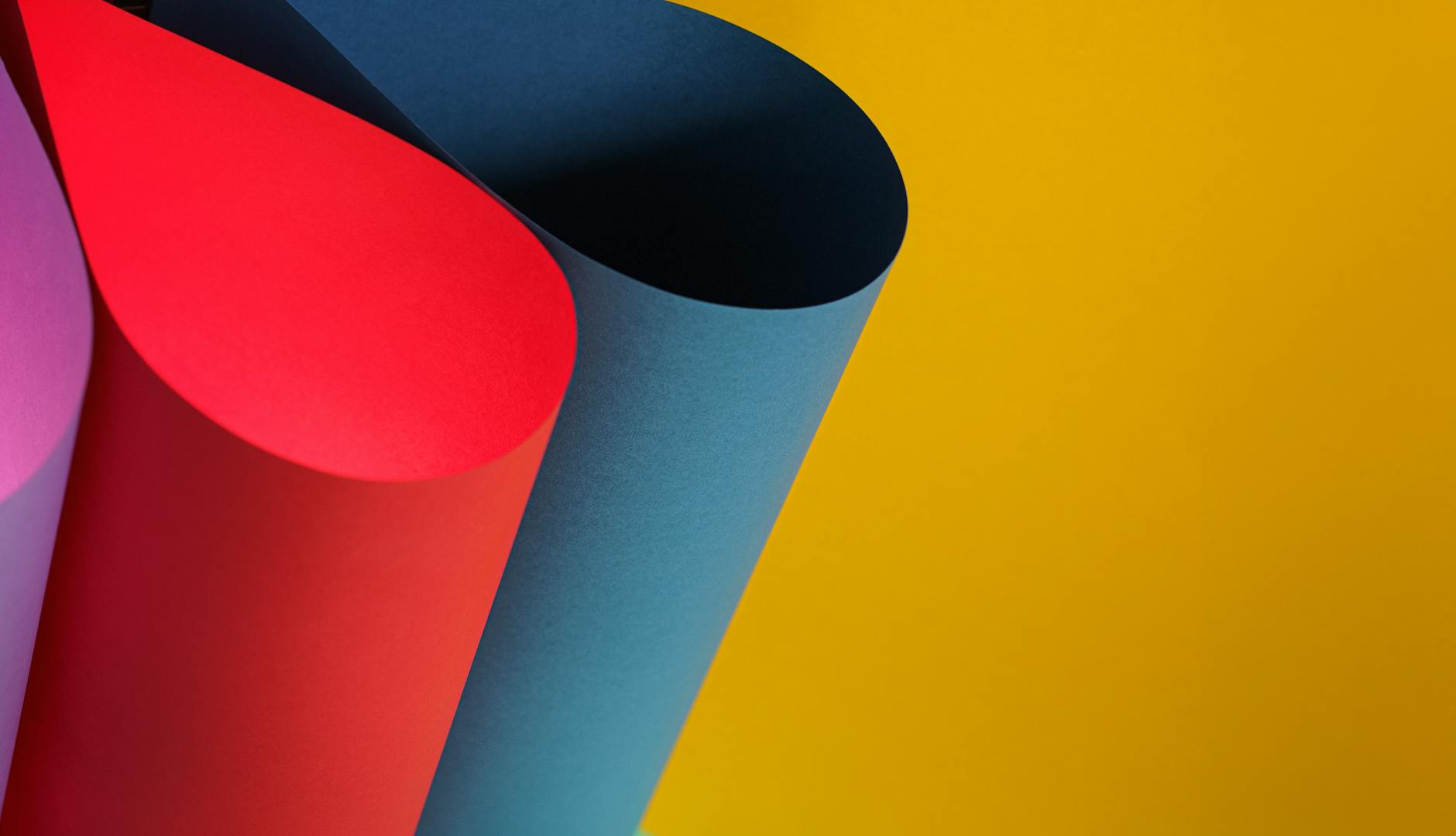 Abstract composition of colorful paper rolls against a vibrant yellow background.
