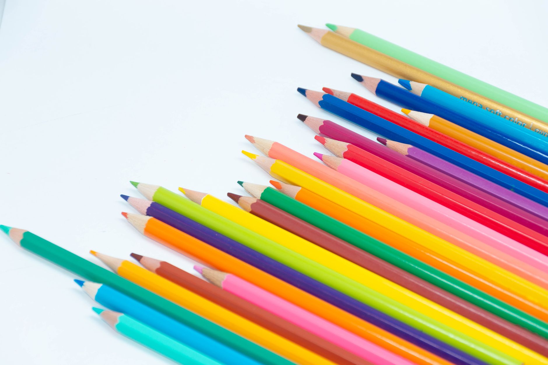 A collection of vibrant colored pencils arranged on a white surface for art projects.