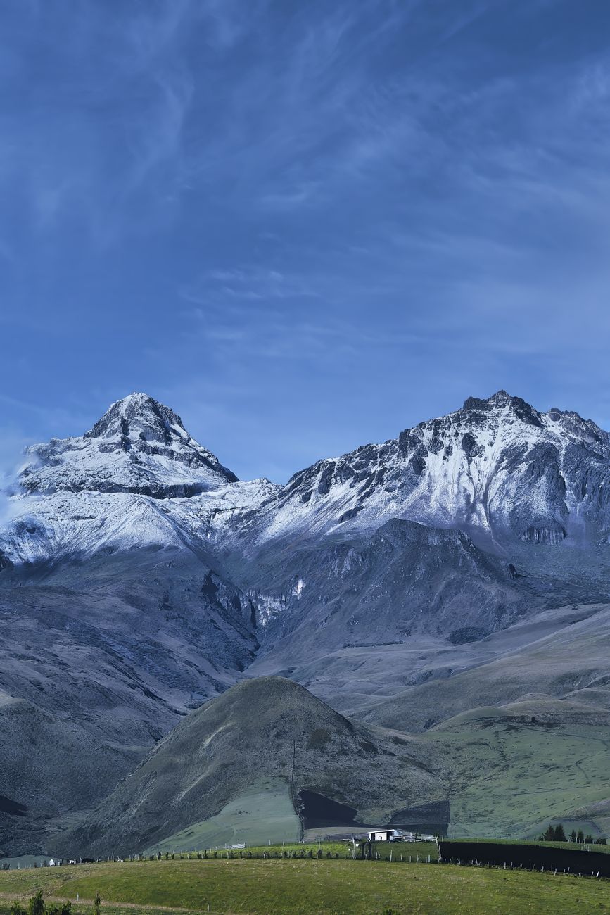 Stunning view of snowcapped mountains with rocky peaks against a clear blue sky and green valley.