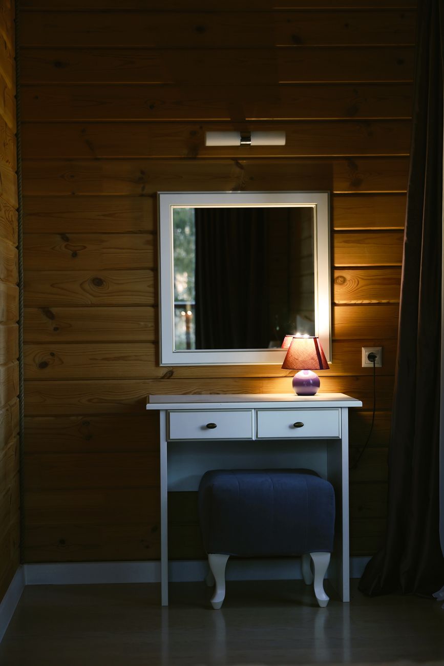 Elegant vanity table with a lamp in a warmly lit wooden interior.
