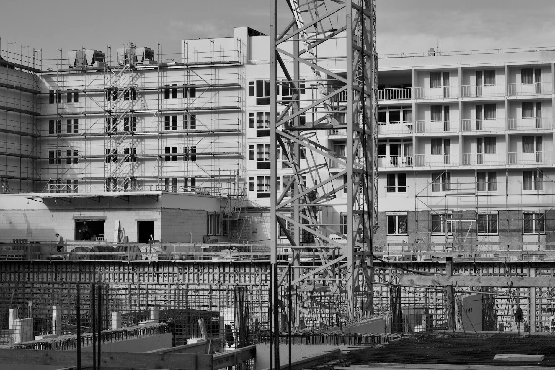 A monochromatic view of a building under construction with scaffolding and cranes.