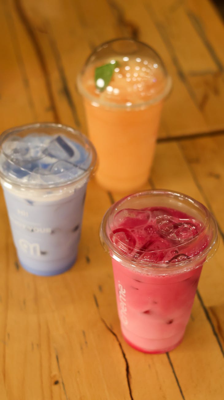 Three vibrant iced drinks on a wooden table captured indoors.