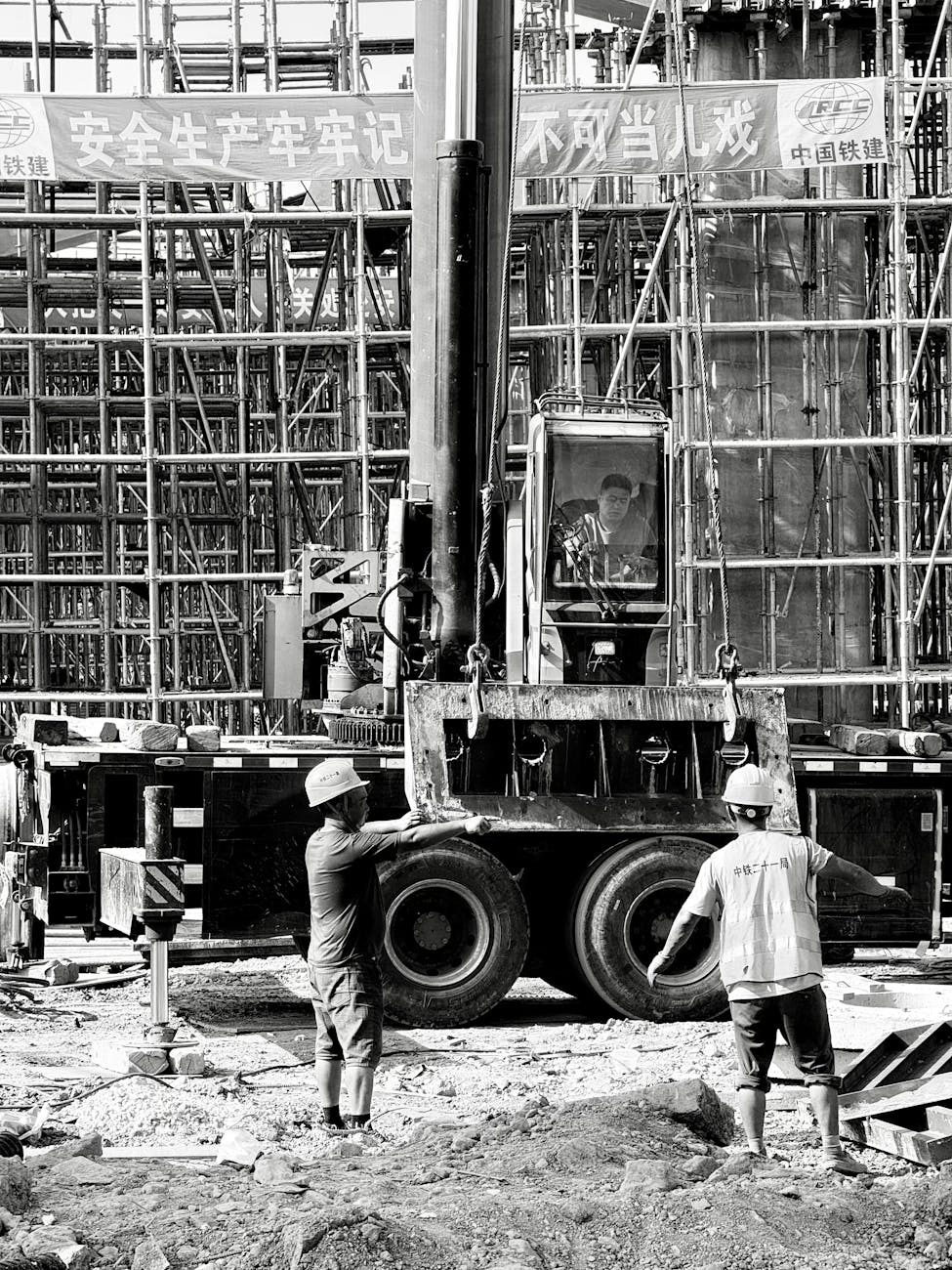 Black and white image of workers and crane at Shanghai construction site, showcasing teamwork and machinery.