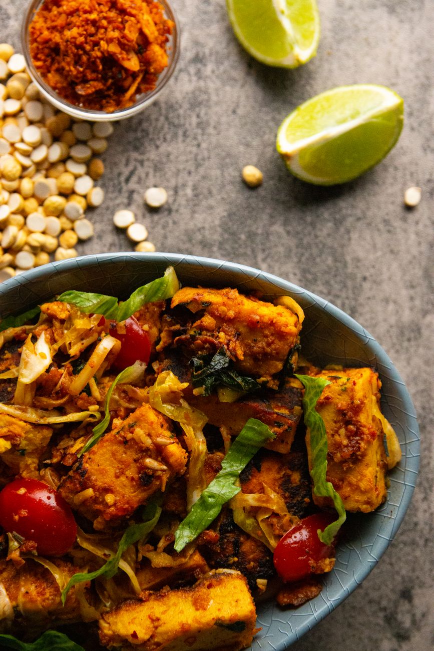 Tasty Indian paneer dish garnished with lettuce and cherry tomatoes, served with lime.