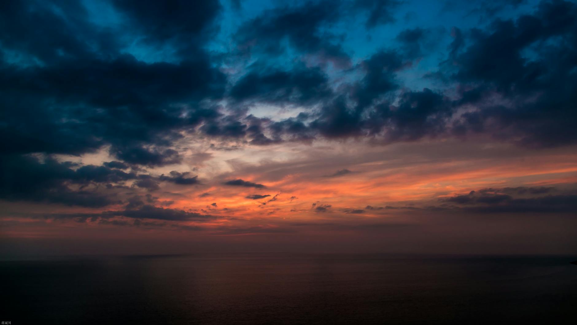 A vibrant sunset with dramatic clouds over a calm ocean. Perfect for serene and atmospheric visuals.
