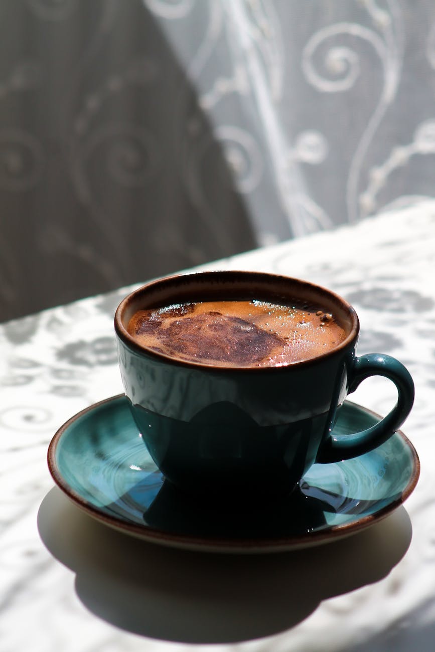 A close-up of a beautifully brewed Turkish coffee in a classic cup with natural sunlight.