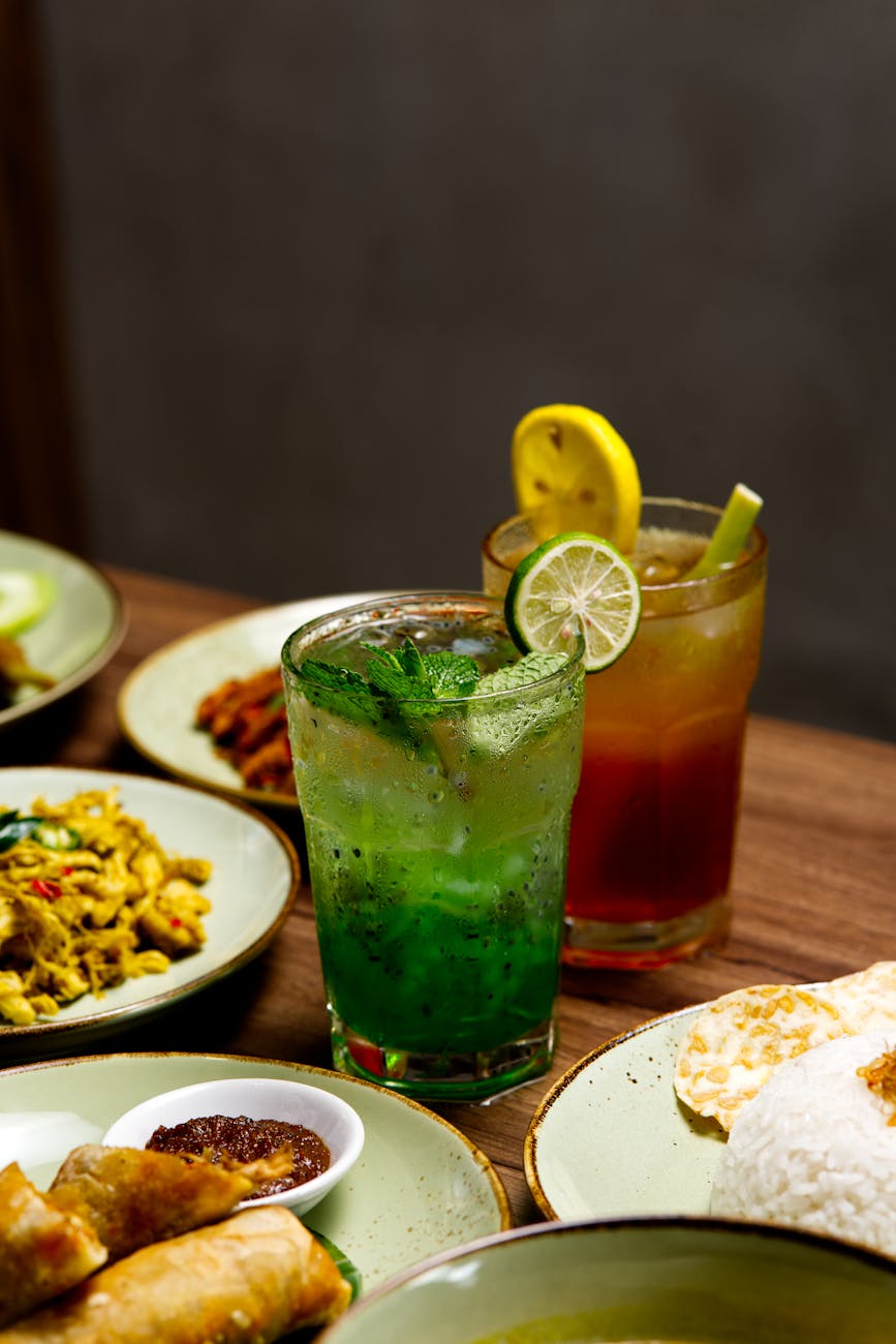 Mint and lemon drinks with a spread of Asian cuisine dishes. Refreshing and vibrant meal setting.